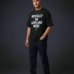 Male model in a three-quarter pose, showcasing the shoulder drop of the black t shirt oversized and the paper plane graphic.