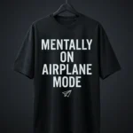 The signature Mentally On Airplane Mode black t shirt oversized hanging on a black hanger against a dark grey background.