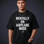 A close-up view of a male model wearing our black t shirt oversized with the "MENTALLY ON AIRPLANE MODE" print.