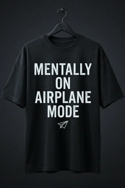 The signature Mentally On Airplane Mode black t shirt oversized hanging on a black hanger against a dark grey background.