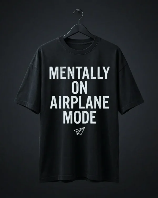 The signature Mentally On Airplane Mode black t shirt oversized hanging on a black hanger against a dark grey background.
